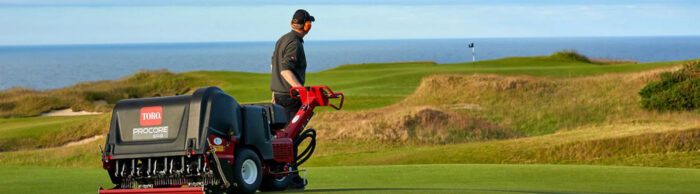 Man carrying aeration equipment on a golf course